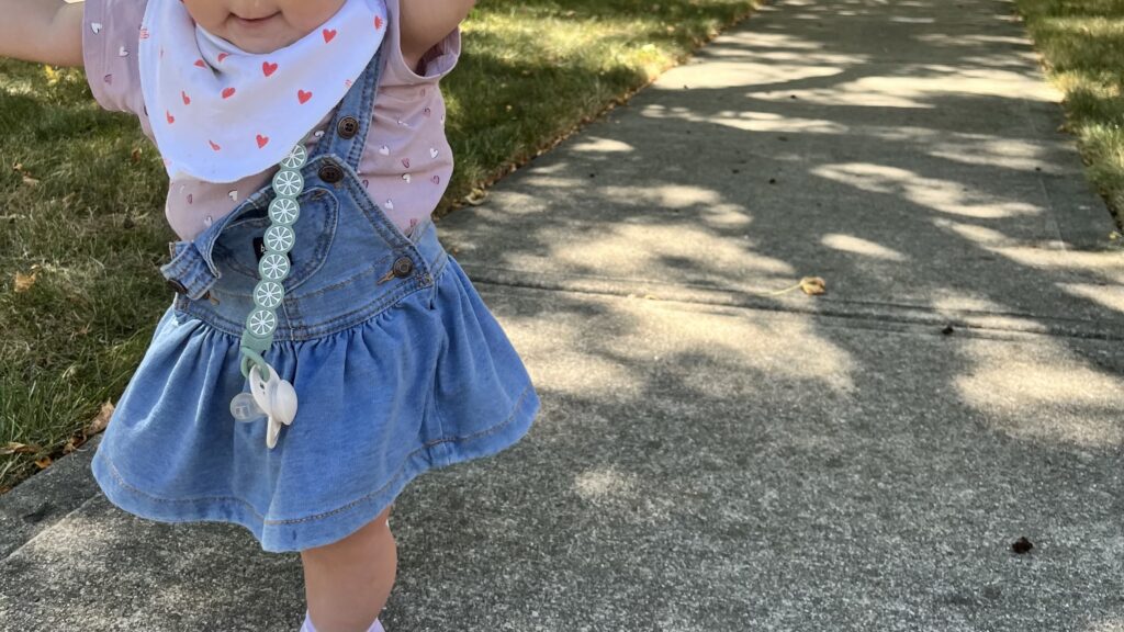 1歳の女の子が外でよちより歩きをしている様子を撮影した写真。